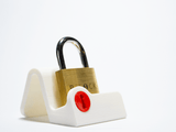 The B-Lock by Boaz Feldman displayed on a white stand, a solid brass puzzle that's fun to solve and share.