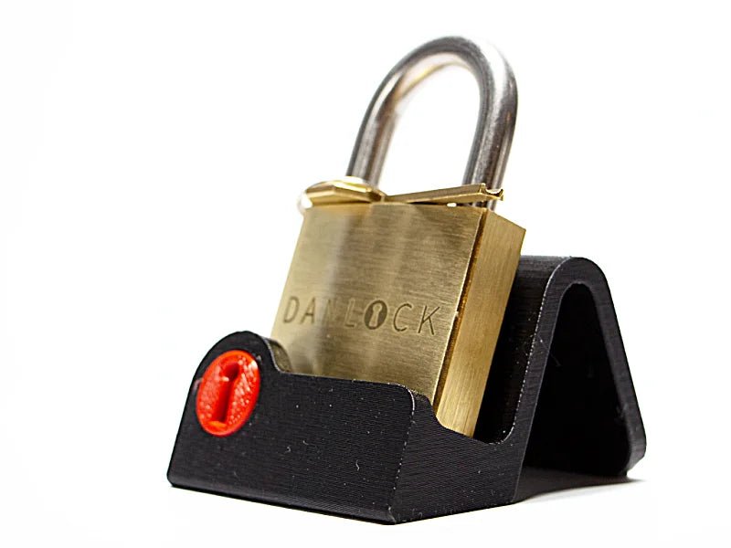 The iconic DanLock mechanical puzzle lock resting on a custom black display stand. A striking corporate office executive gift or minimalist desktop accessory designed to test problem-solving and lateral thinking.