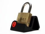 The Loki puzzle lock resting on a black display stand with a red keyhole detail, sold separately for a home office or study.